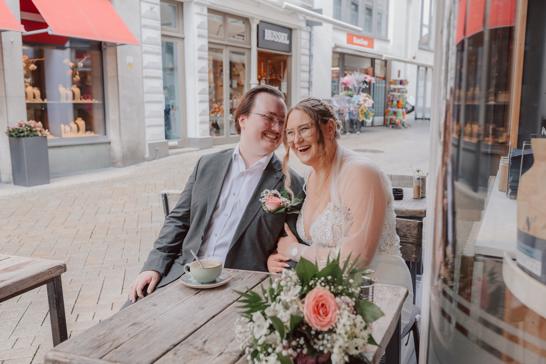 Marieke und Thies lachen zusammen an einem Cafe-Tisch